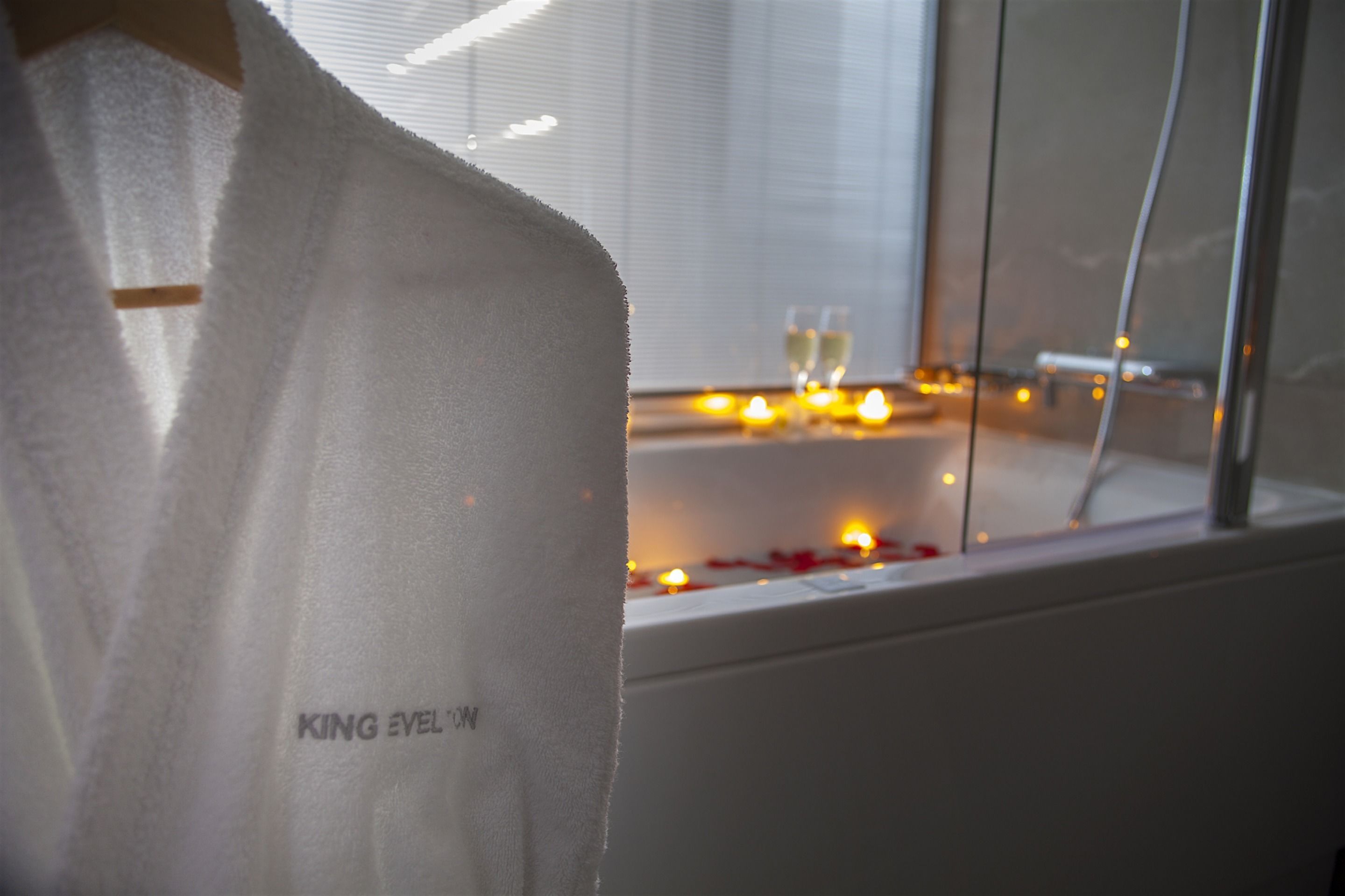 A bathroom with a bathtub, candles, and a window.