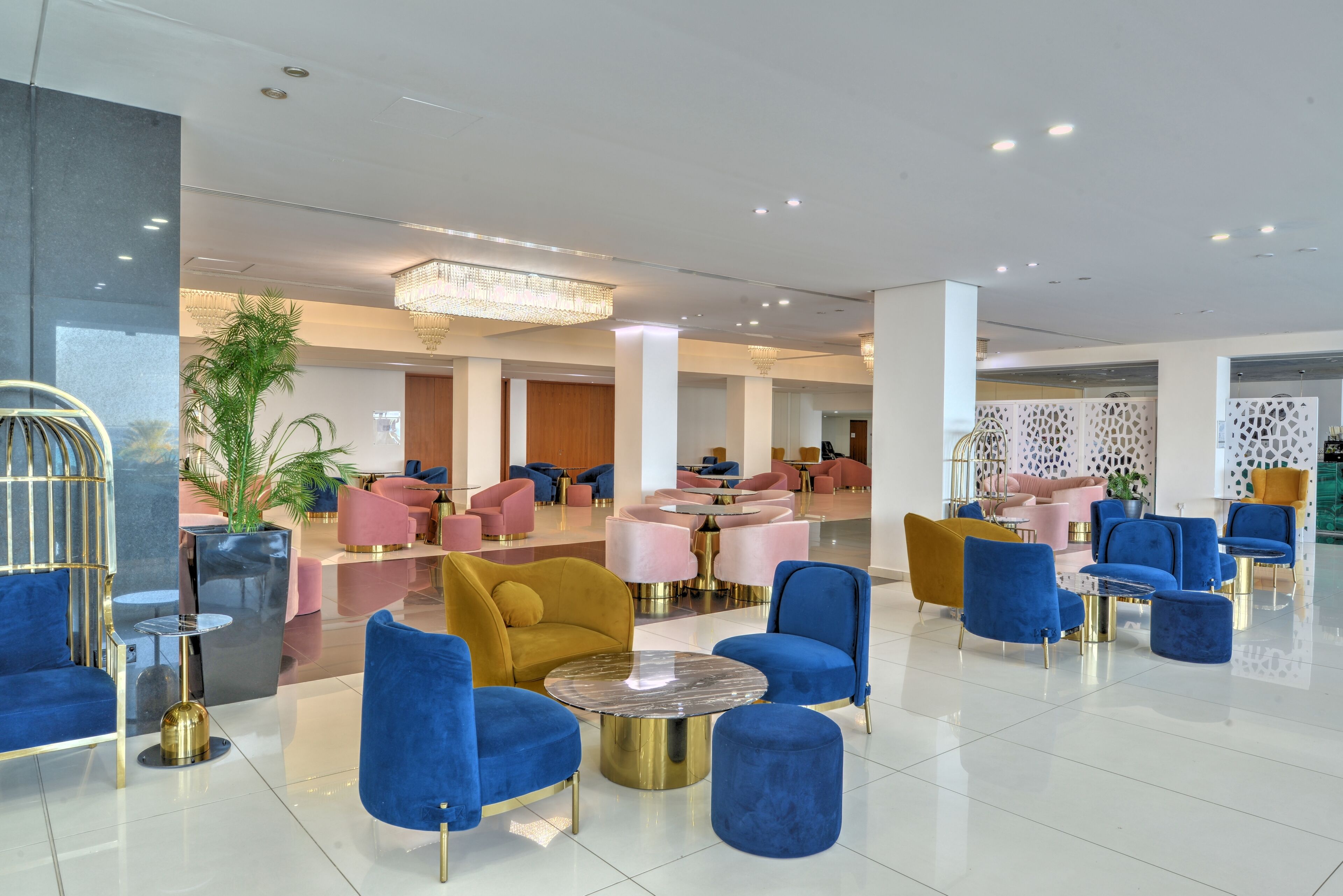 A spacious lobby with multiple seating areas, including round tables and sofas, and a large chandelier.