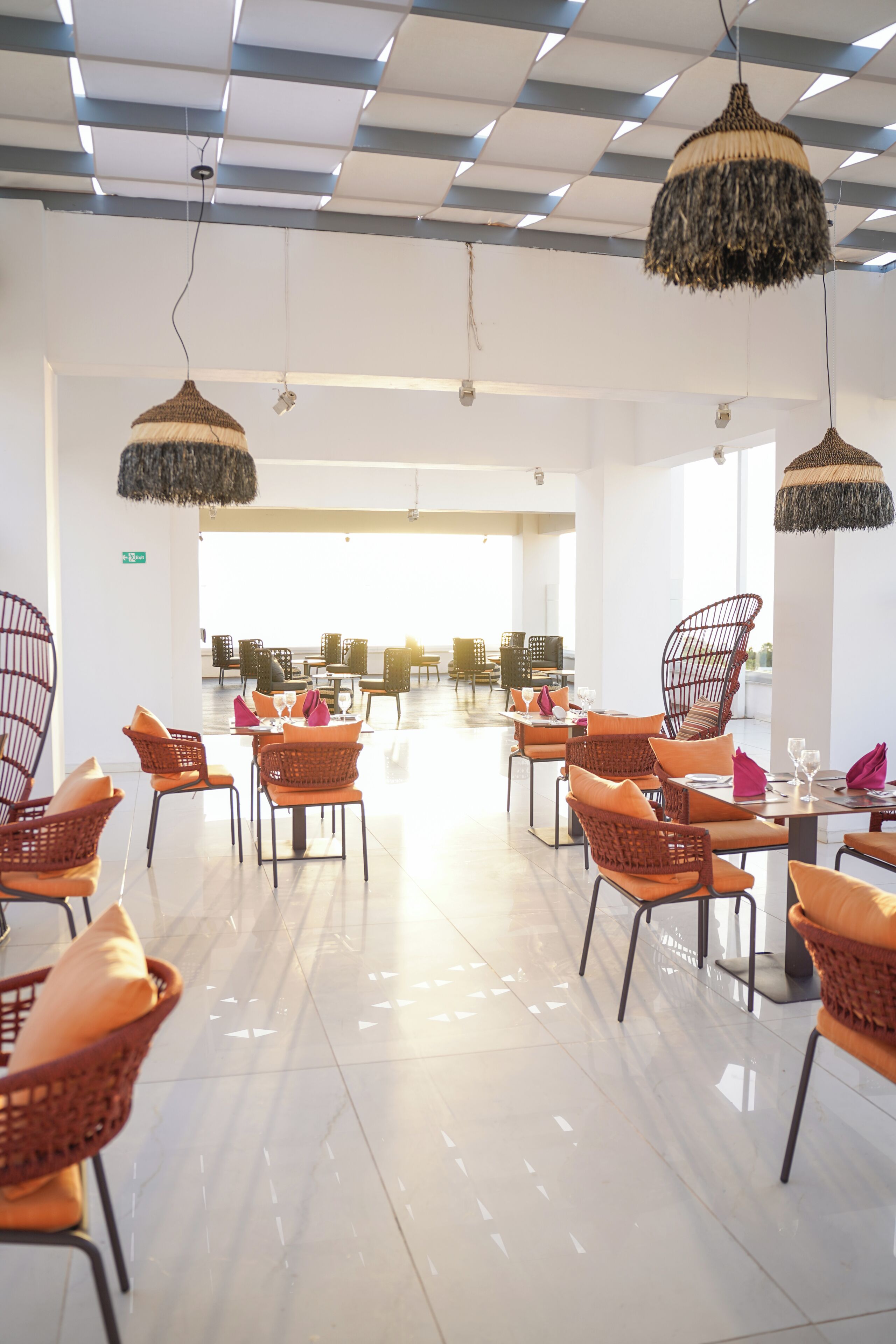 A spacious indoor area with modern wicker furniture and pendant lighting.