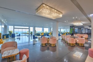 A spacious hotel lobby with modern furnishings, large windows offering views, and elegant lighting fixtures.