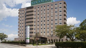 Un hotel de varios pisos con un letrero que dice 'Hotel Route Inn' y un letrero que indica 'Hotel Route Inn' en japonés.