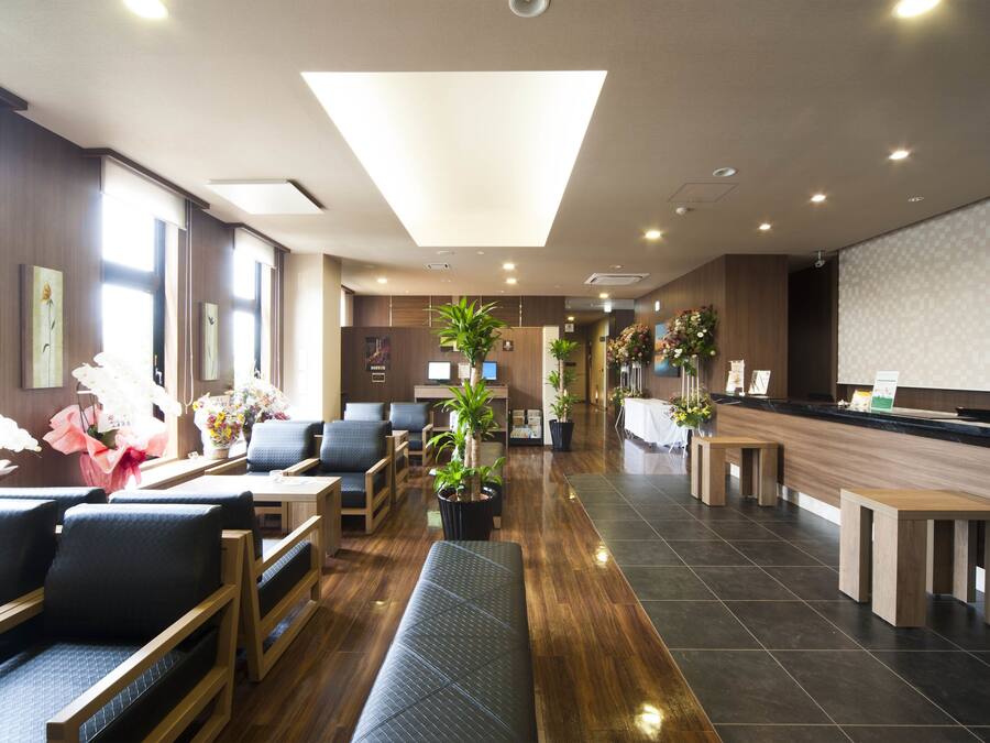 A hotel lobby with seating areas, a reception desk, and potted plants.