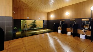 Un baño moderno con paneles de madera, separadores de vidrio y varios lavamanos.