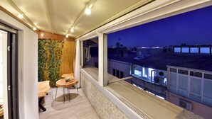 A balcony with a view of the city at night, wooden flooring, and a small table with chairs. - Sunlife Hotel Old City (Istanbul)