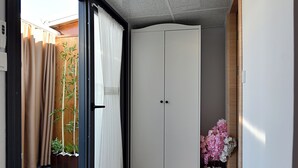 A hallway with a sliding glass door leading to an outdoor area, a white wardrobe, and a small table with flowers. - Sunlife Hotel Old City (Istanbul)
