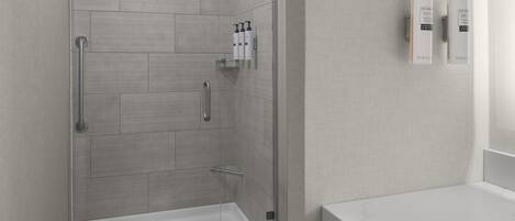 A modern bathroom with a glass-enclosed shower, a white sink, and toiletries on the wall.