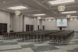 A conference room with rows of chairs, a large screen, and chandeliers. - Embassy Suites by Hilton Tuscaloosa Alabama Downtown (Tuscaloosa)