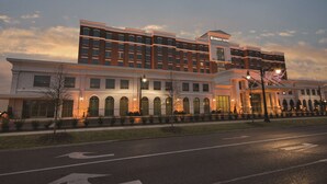 A hotel with a modern architectural design, featuring a prominent entrance with arched windows and a sign for 'EMBASSY SUITES'. - Embassy Suites by Hilton Tuscaloosa Alabama Downtown (Tuscaloosa)