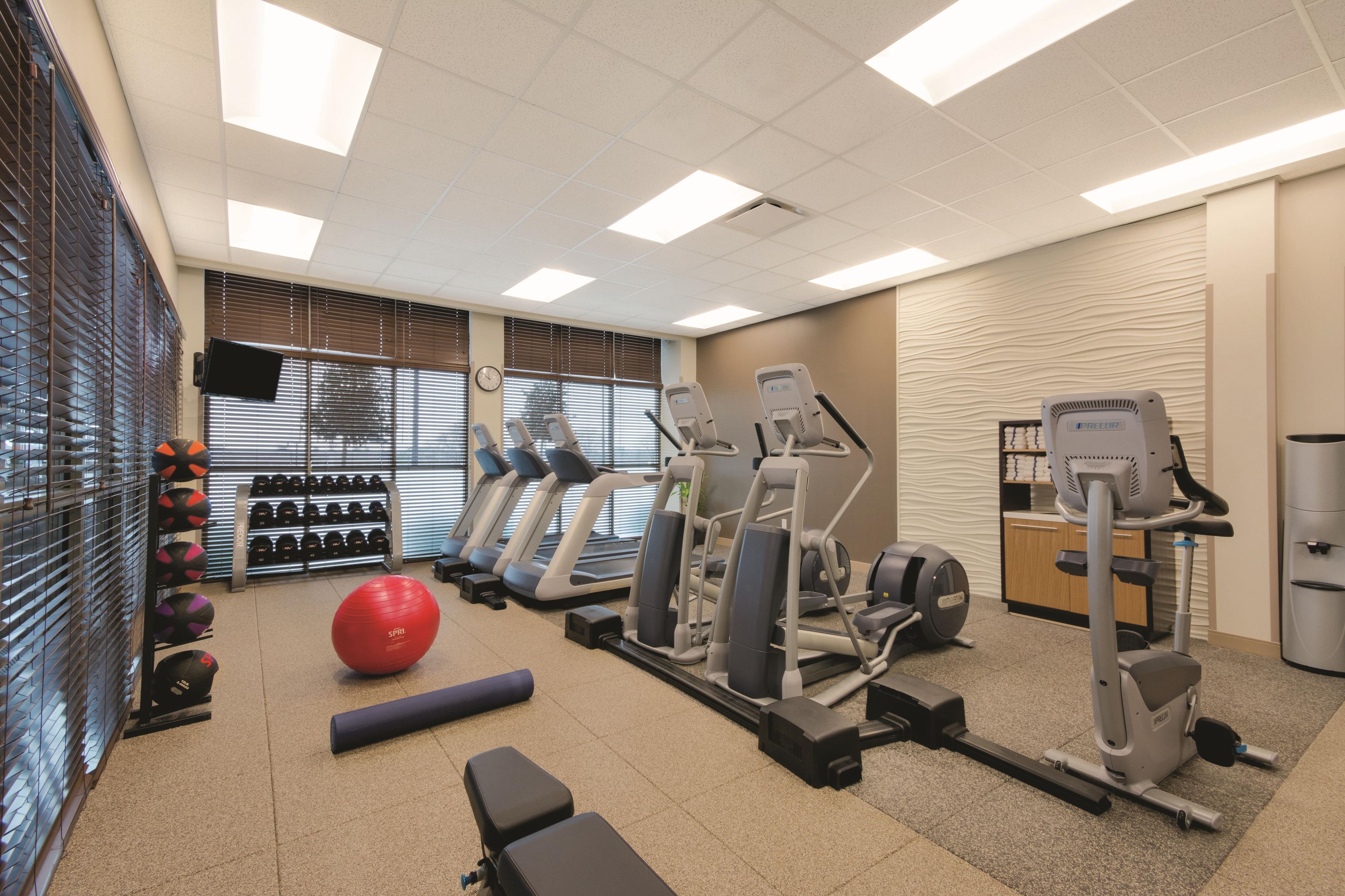 Ein Fitnessstudio mit Laufbändern, Crosstrainern, Kurzhanteln und Übungsbällen.