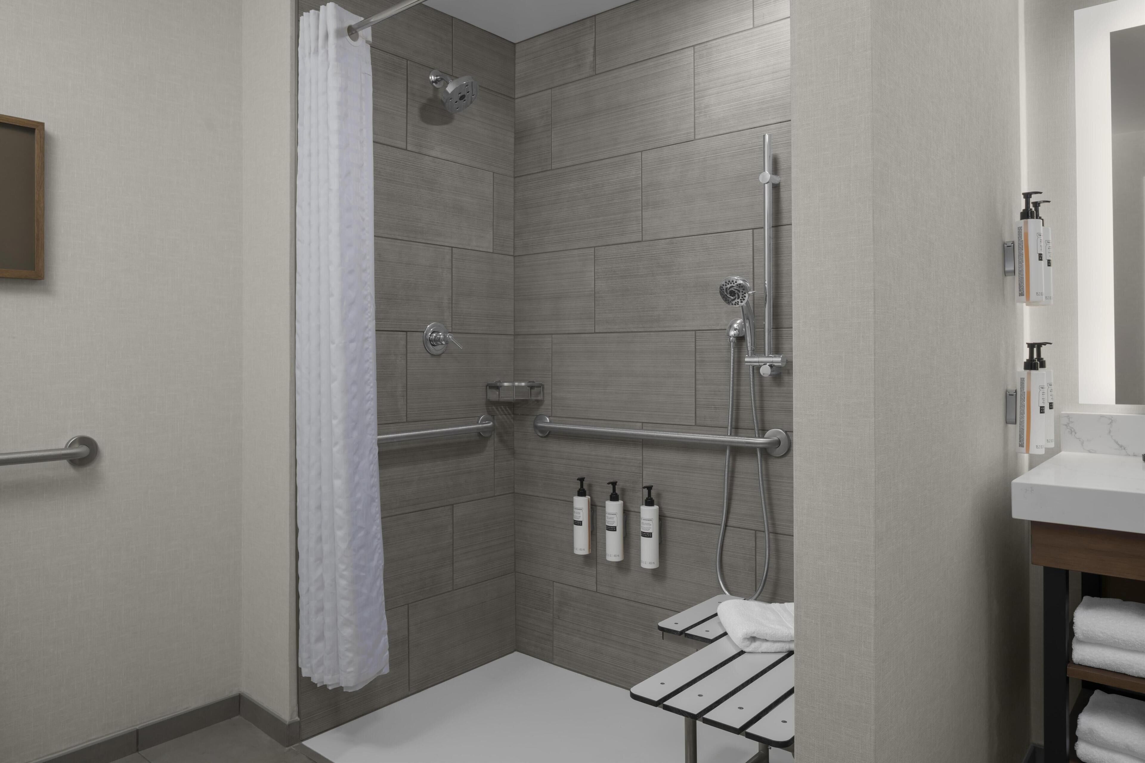 Un baño moderno con ducha, barras de apoyo, toallero y artículos de aseo.