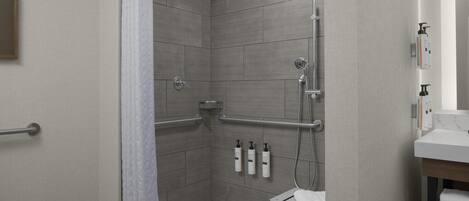 Un baño moderno con ducha, barras de apoyo, toallero y artículos de aseo.