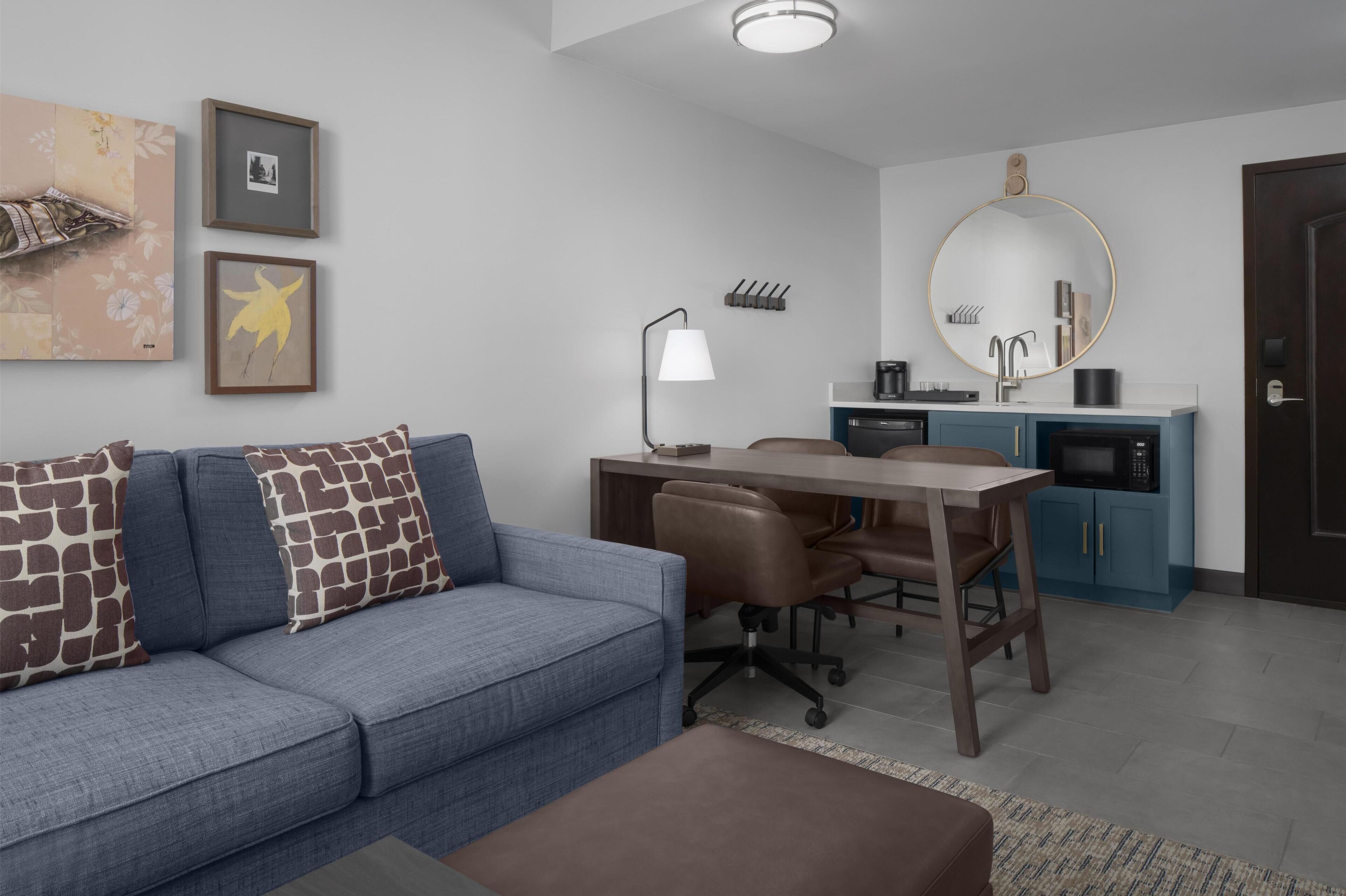 A modern living room with a sofa, a desk, and a kitchen area.
