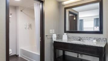 Un baño moderno con cabina de ducha, tocador de madera oscura y un espejo grande.