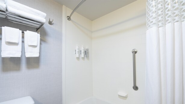 A bathroom with a white bathtub, a shower with a grab bar, and a towel rack with folded towels. - Hampton Inn Lewiston-Auburn (Lewiston)