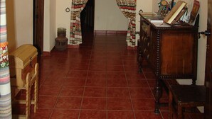 Un pasillo con una puerta de madera, una silla de madera, un escritorio de madera y una lámpara de pared.