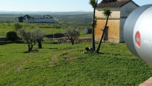 Paisaje rural con un edificio blanco, una construcción pequeña con techo de tejas y cielo despejado.