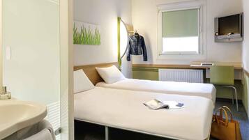 Una camera d'albergo con due letti, una scrivania, uno specchio, una televisione e un bagno.