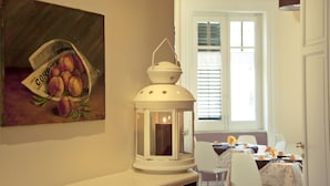 A dining area with a table set for two, a white lantern, and a painting of peaches on the wall. - 174 Via Roma (Palermo)