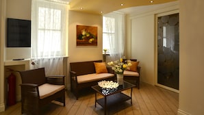 A living room with a sofa, two armchairs, a coffee table, and a painting on the wall. - 174 Via Roma (Palermo)
