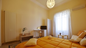 A hotel room with a large bed, a desk with a computer, a TV, and a window with curtains. - 174 Via Roma (Palermo)