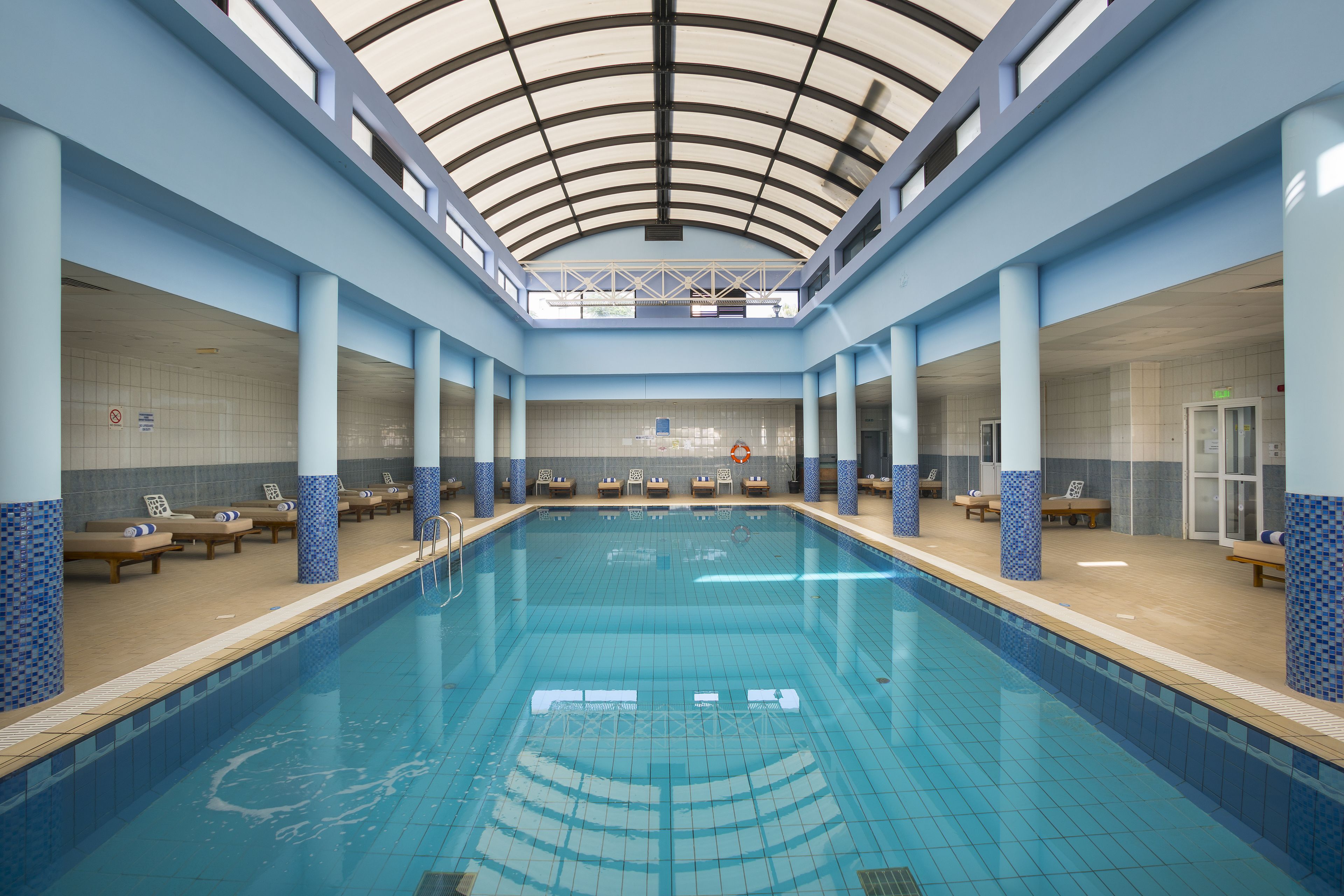 An indoor swimming pool with a high ceiling and blue-tiled walls.