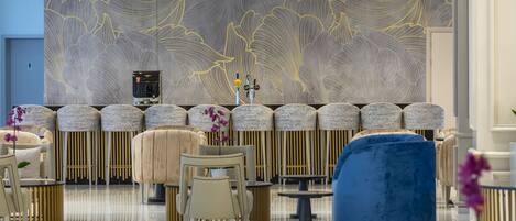A modern lobby with a patterned wall, a reception desk, and seating areas.