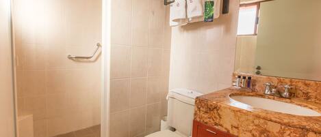 A bathroom with a shower, toilet, sink, and vanity.