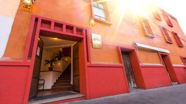 Un edificio con fachada roja, una escalera que conduce a una entrada y un letrero sobre la puerta.
