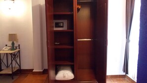 Un armario de madera con repisa para microondas integrada, una mesita con lámpara y una cortina en la ventana.