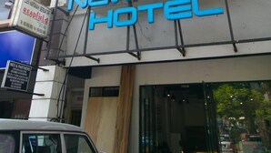 The exterior of the New Town Hotel with a signboard, a multi-story building, and a parked car in front. - New Town Hotel Sunway Metro, Bandar Sunway (Petaling Jaya)