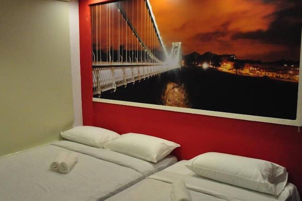 Hotelkamer met een bed en een groot raam dat uitzicht biedt op een brug 's nachts.