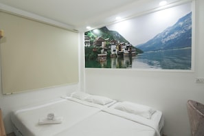 Una camera d'albergo con un letto, una finestra vista lago e case, e un quadro appeso al muro.