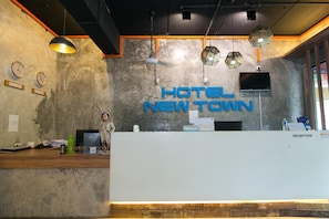 Zona reception dal design moderno, con un'ampia scrivania, diverse orologi e un televisore a parete.