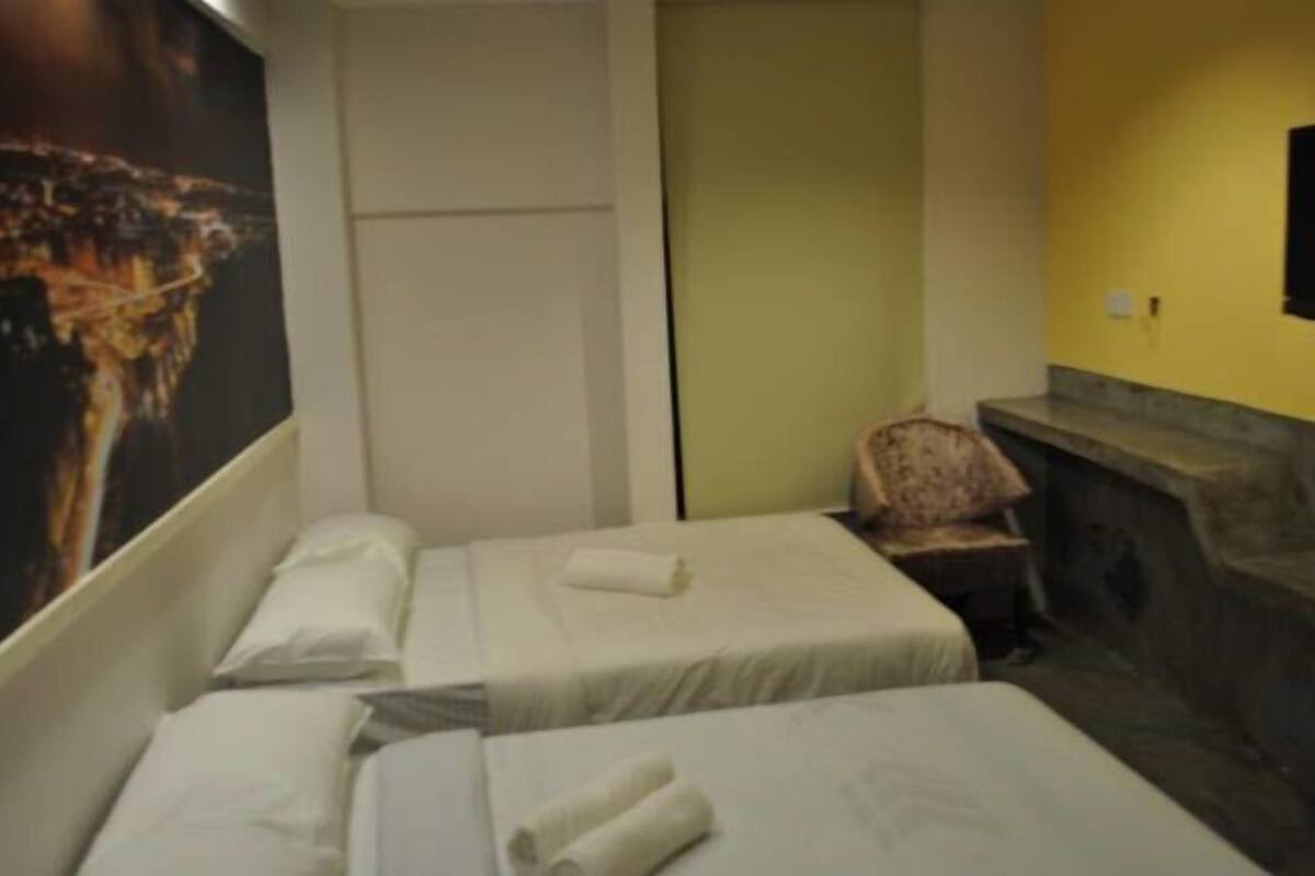 Een hotelkamer met twee bedden, een stoel, een televisie en een stenen bank.