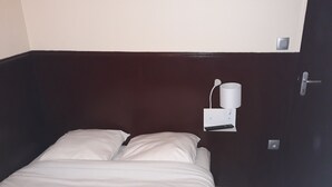 Ein Einzelbett mit weißer Bettwäsche in einem Raum mit dunkelbraunen Wänden.