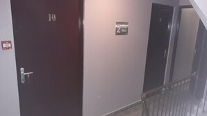 Ein Flur mit einer dunkelbraunen Tür, die mit der Nummer 10 gekennzeichnet ist, einem Schild für den 2. Stock und einem Metallgeländer auf der rechten Seite.