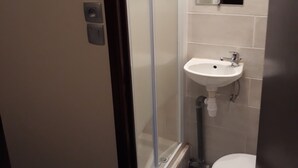 Ein Badezimmer mit Duschkabine aus Glas, einem weißen Waschbecken und einer Toilette.