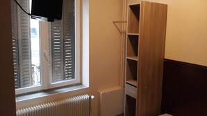 Ein Zimmer mit Fenster, Heizkörper und einem Holzschrank.