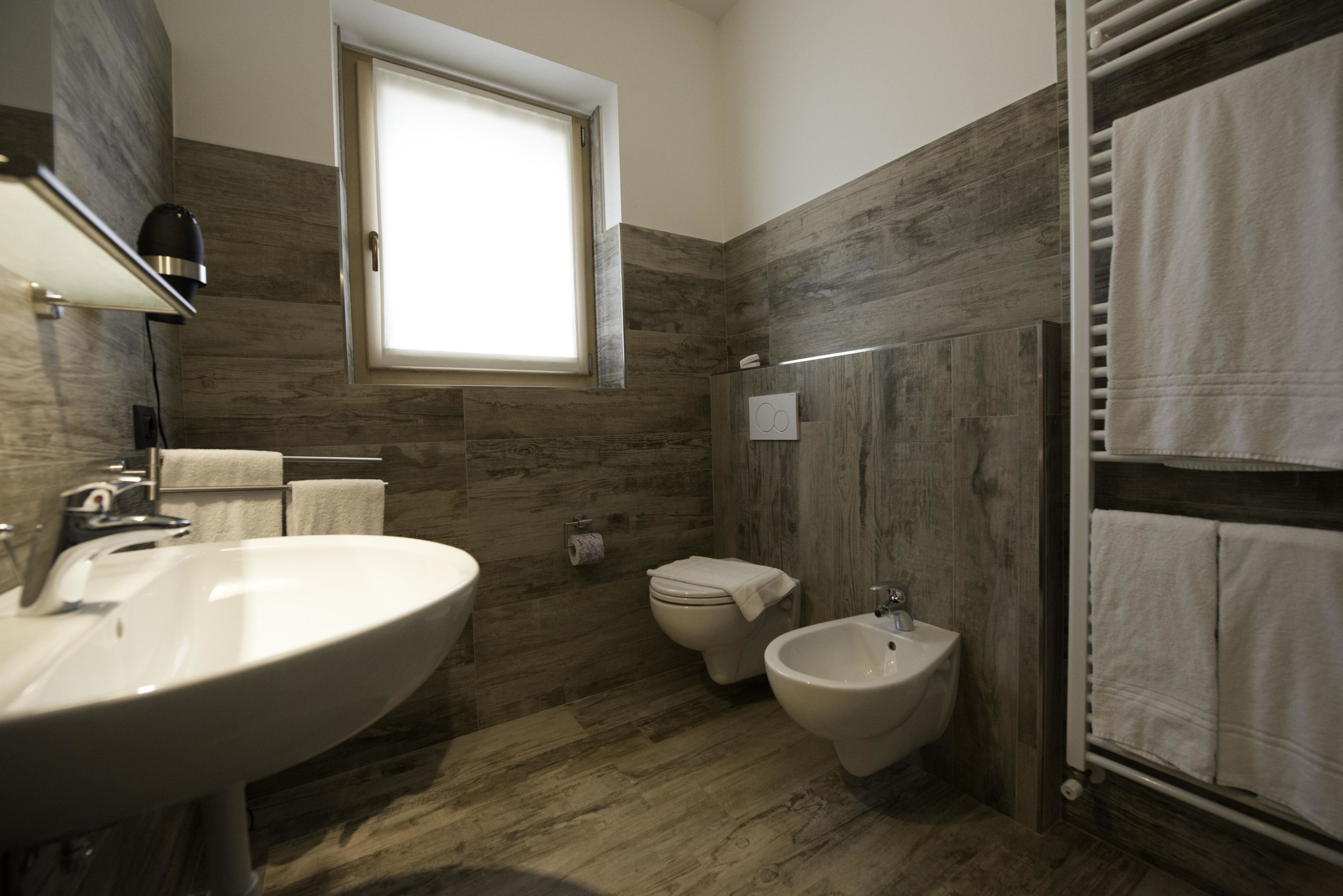 A bathroom with a large sink, bidet, toilet, and towel rack.