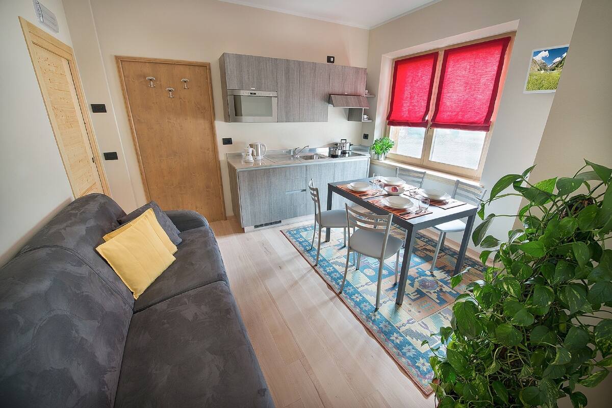 Un espacio habitable compacto con sofá, mesa de comedor y kitchenette.