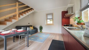 A modern kitchen with wooden stairs, a dining area with a table set for four, and a small window. - Central Rin (Livigno)