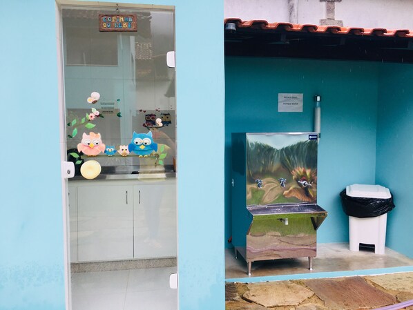 Une chambre dotée d’une kitchenette, d’une fenêtre ornée d’autocollants décoratifs, d’une poubelle et d’un distributeur d’eau.