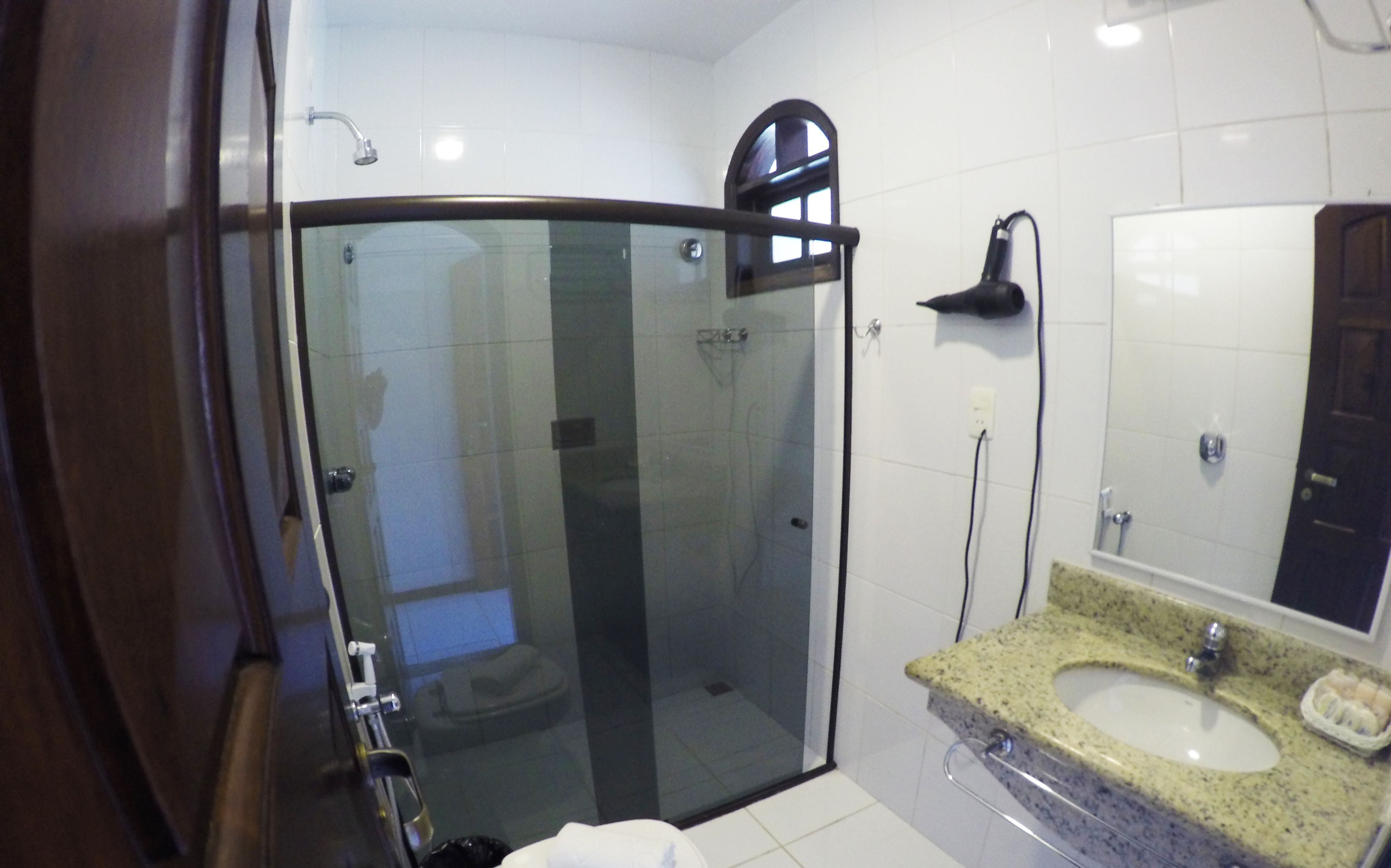 A modern bathroom with a glass-enclosed shower, a granite sink, and a large mirror.
