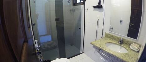A modern bathroom with a glass-enclosed shower, a white toilet, and a granite countertop sink.