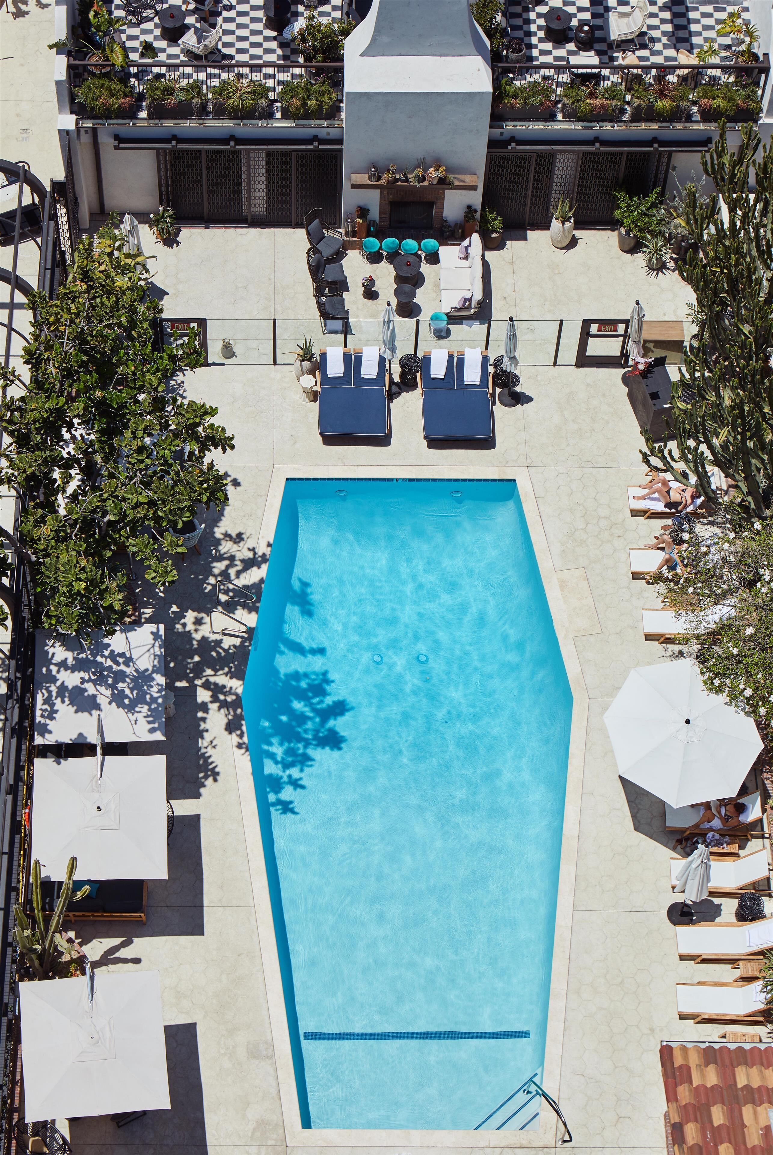 A rectangular swimming pool with lounge chairs and umbrellas around it.