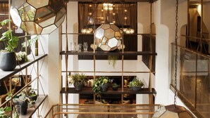 A modern interior with a geometric metal staircase, glass railings, and multiple levels with plants and lighting fixtures. - Hotel Figueroa, Unbound Collection by Hyatt (Los Angeles)