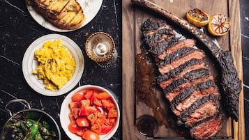 Un filete con marcas de parrilla, un tazón de tomates y un plato de huevos revueltos.