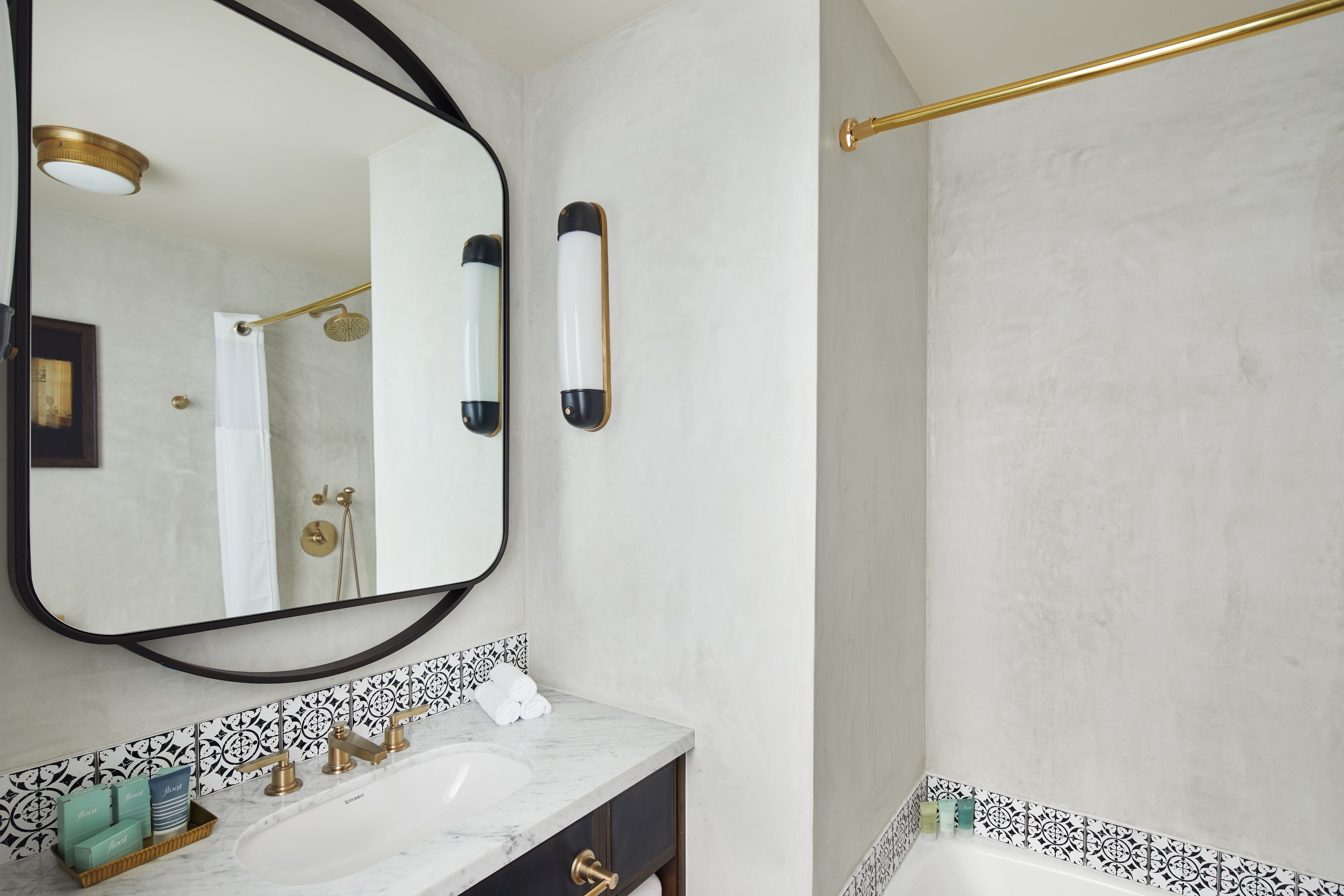 A bathroom with a large mirror, a sink with a marble countertop, and a shower area.
