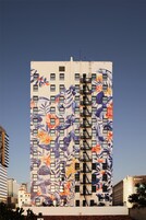 Un edificio alto con un gran mural de flores y hojas tropicales en su fachada.
