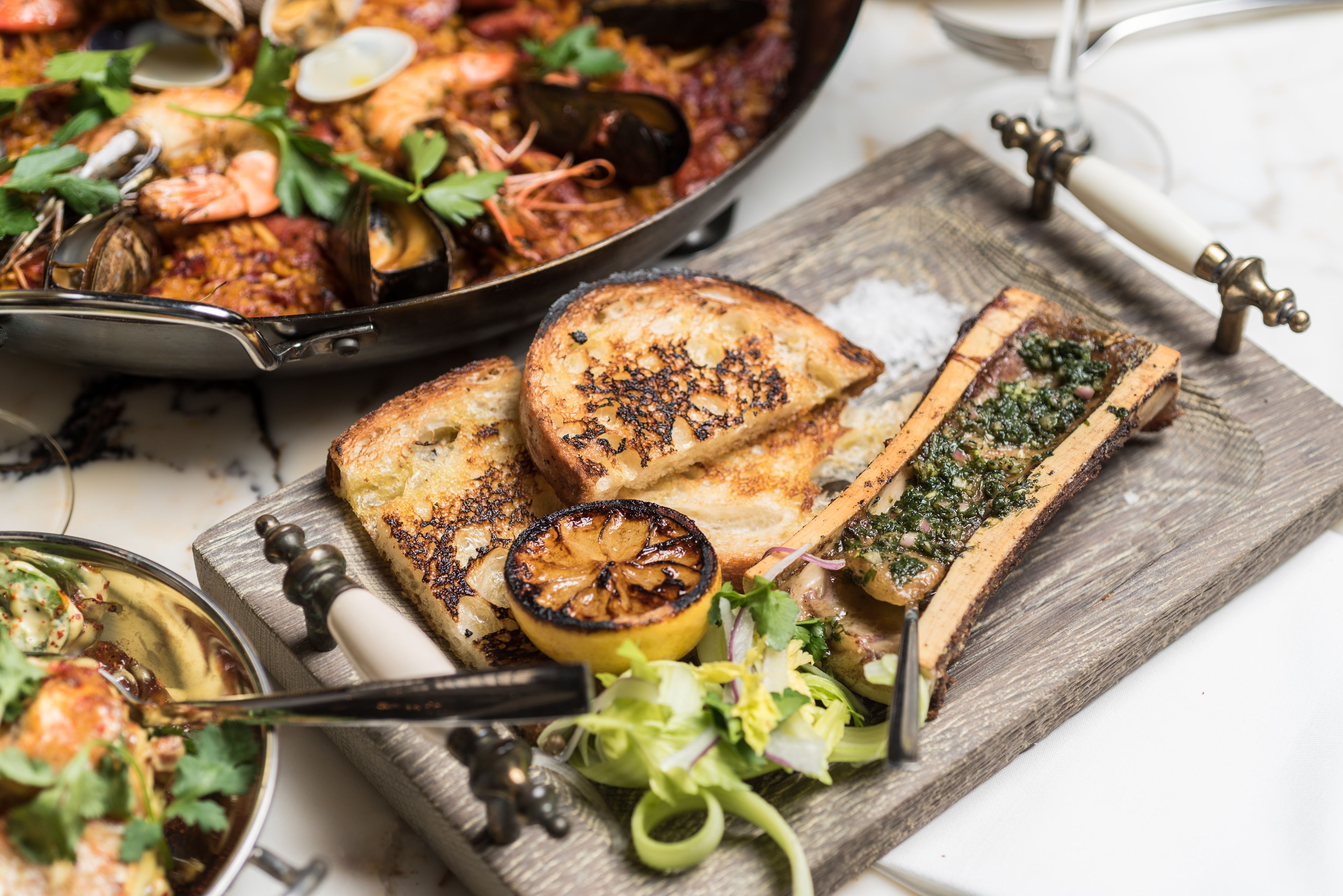 A seafood dish with bread and a wooden board.